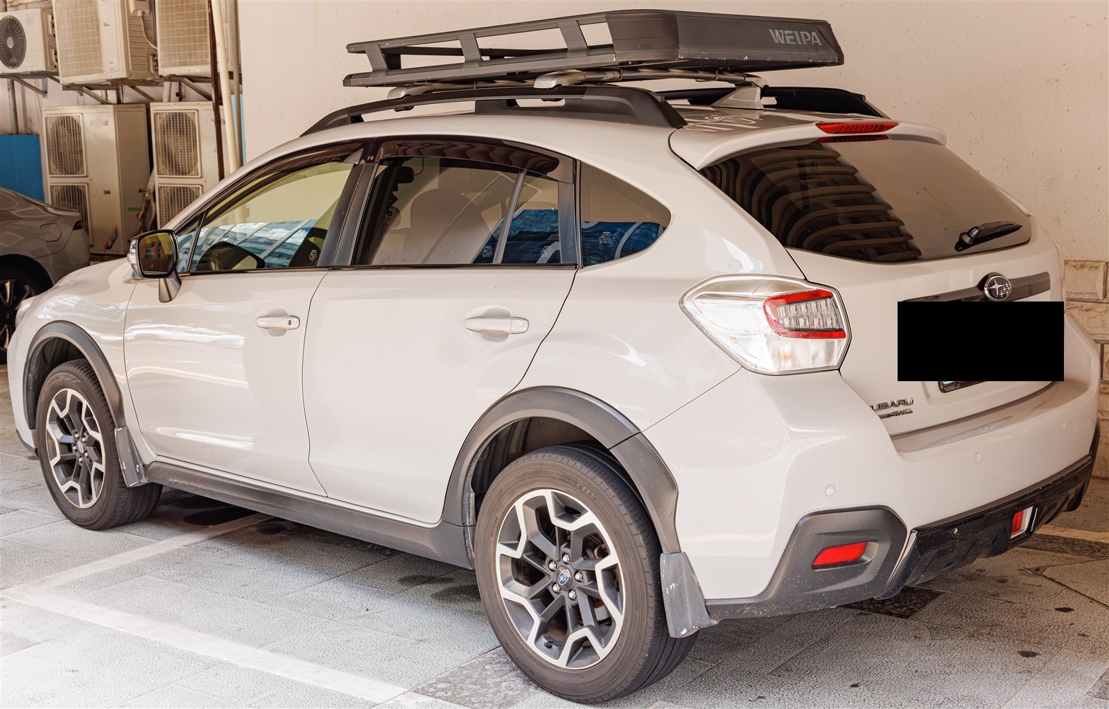 White Subaru Crosstrek with a roof cargo basket, rear three-quarter view