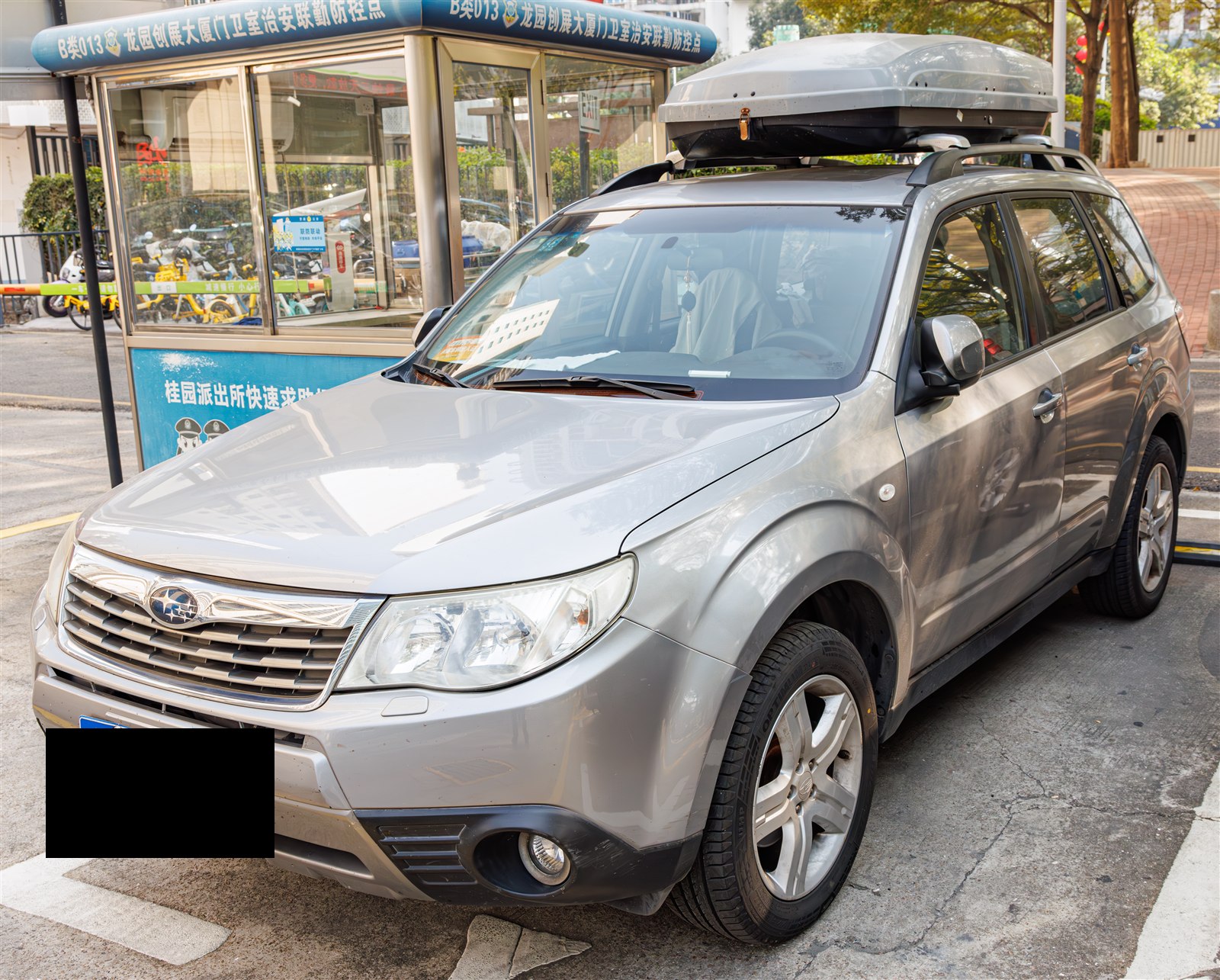 Silver Subaru Forester with a roof cargo box, front three-quarter view