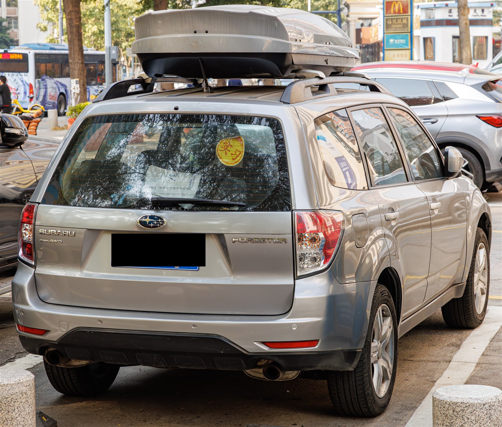 Silver Subaru Forester with a roof cargo box, rear three-quarter view