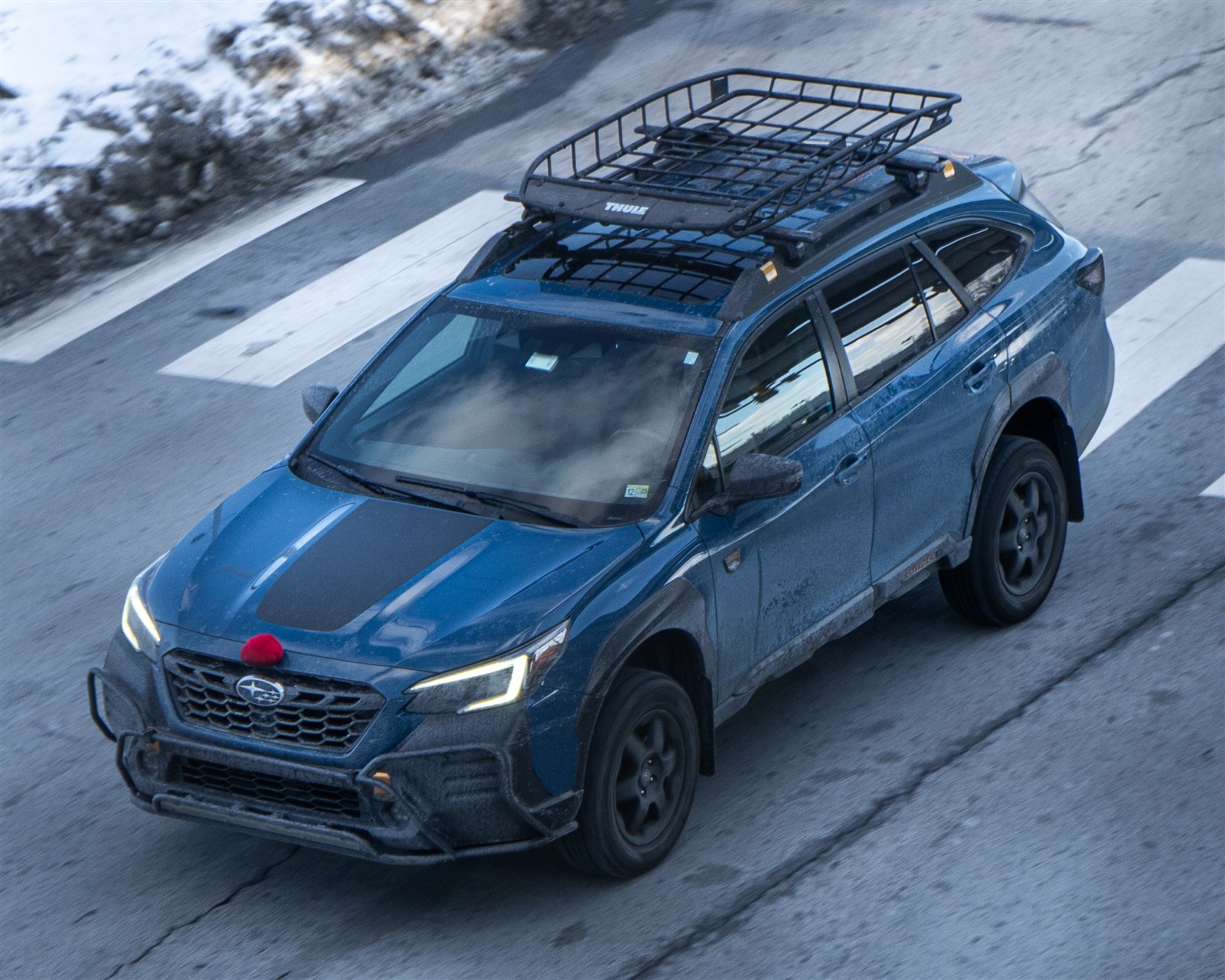 Subaru Outback Wilderness driving with a Thule cargo basket mounted on the roof